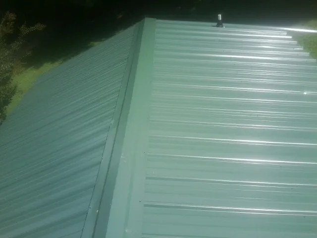 New green metal panels meeting at the ridge of a roof — Flat Roof Repair work by our crew in Maryland Line