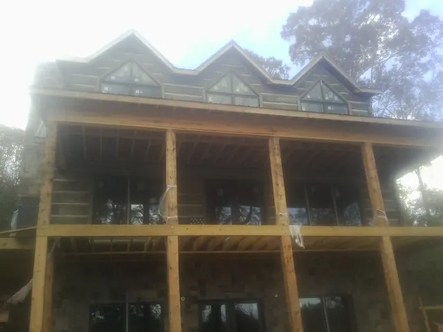 Dormers and porch framing on a large log home under construction — Roof Coating work by our crew in Maryland Line