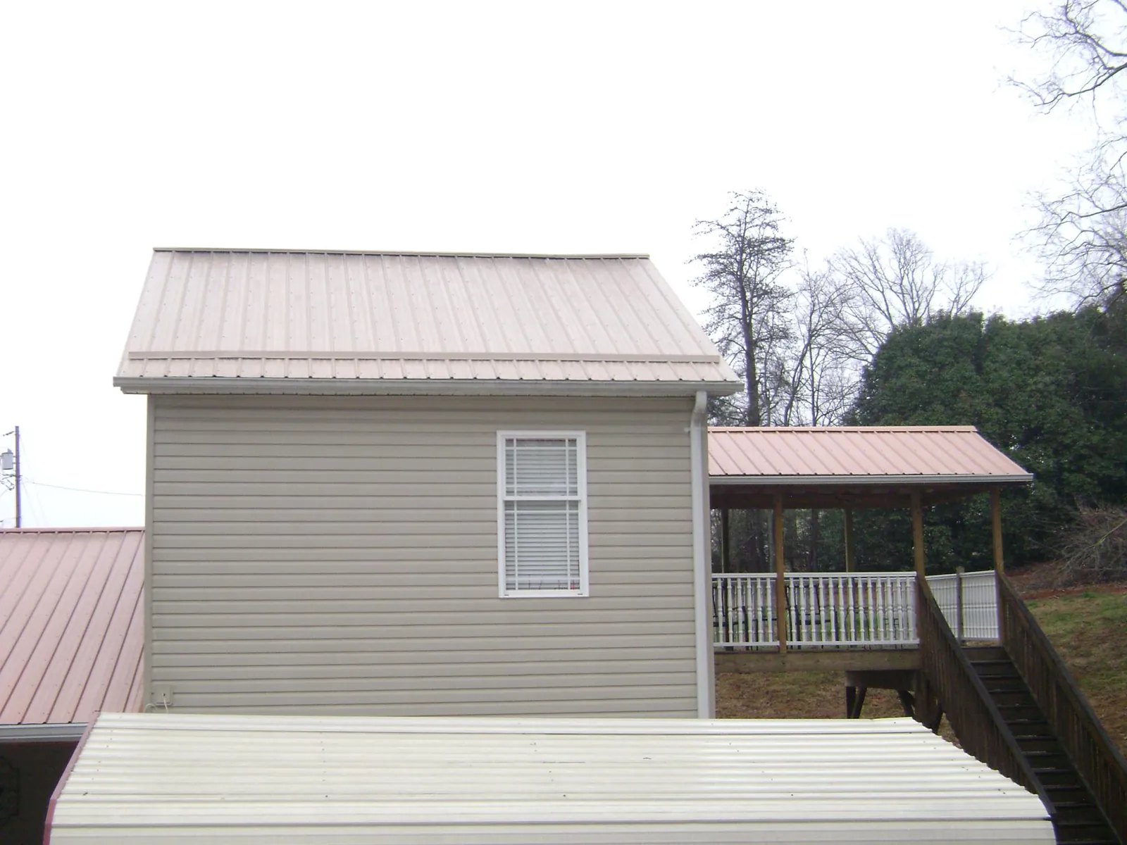 Tan metal roofs on a two story addition and attached porch, from a Roof Replacement job in Maryland Line