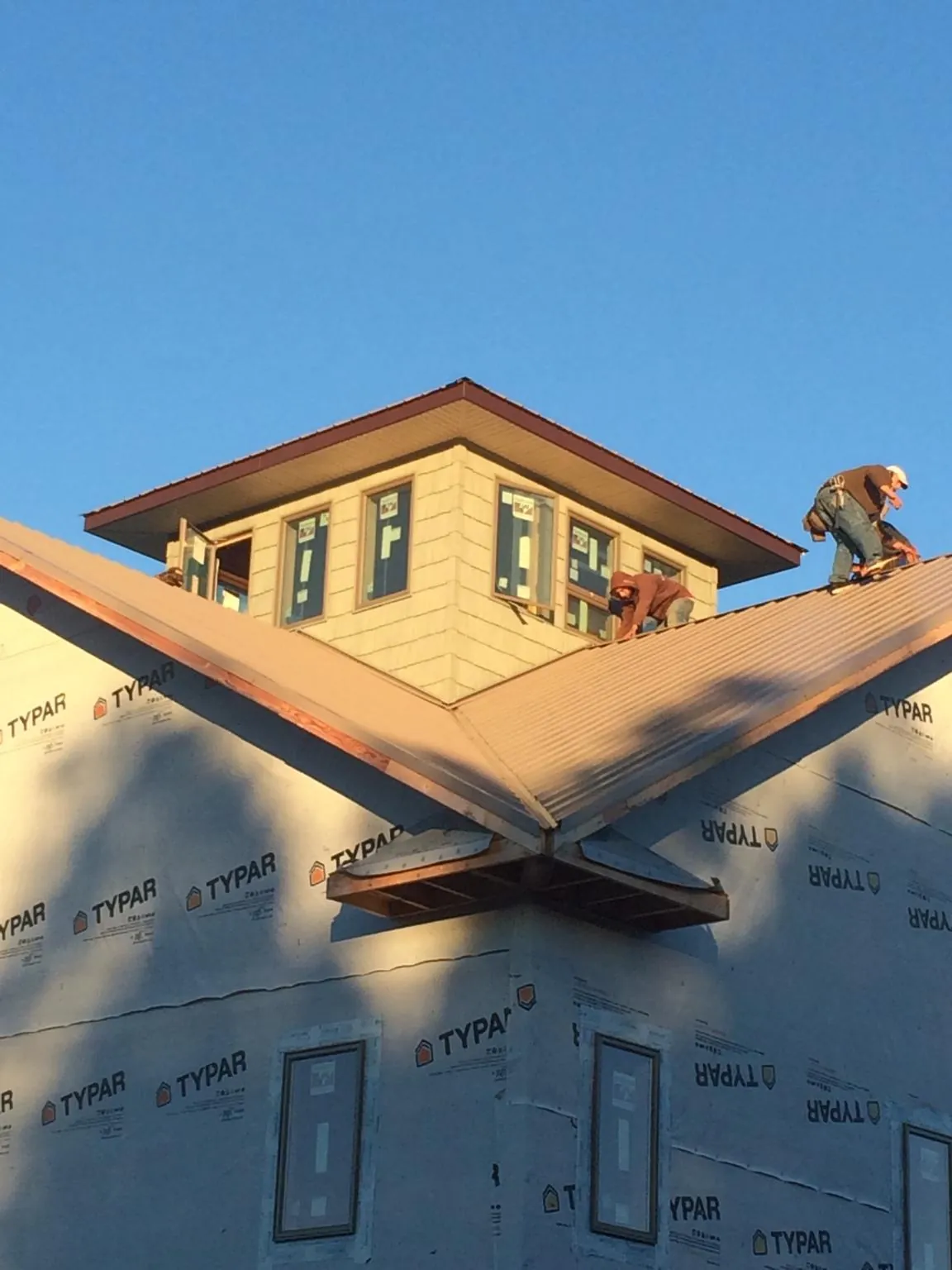 Roofers working around a rooftop cupola on a new metal roof at sunset — Roof Waterproofing in Maryland Line by Roofing Brothers